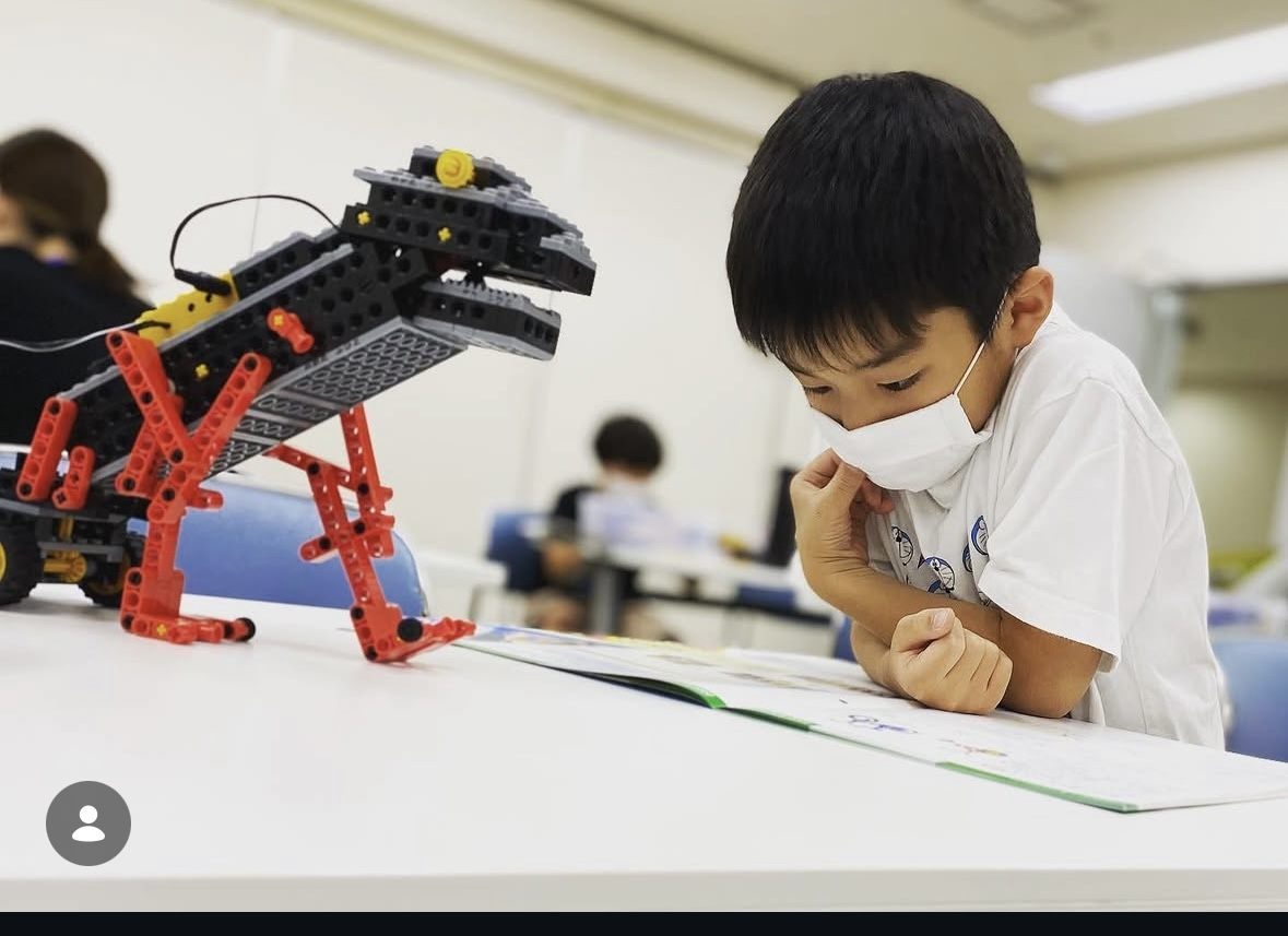 テキストを見ながらロボットを組み立てる生徒