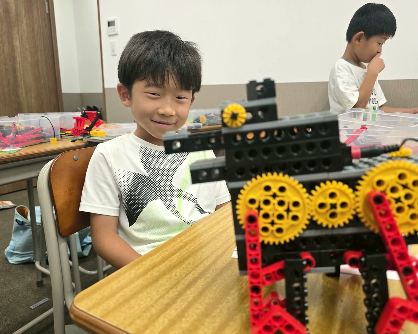 完成したギアのロボットを前に笑う生徒
