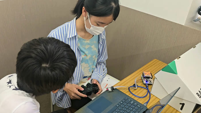 講師と一緒にロボットの動きを確かめる生徒