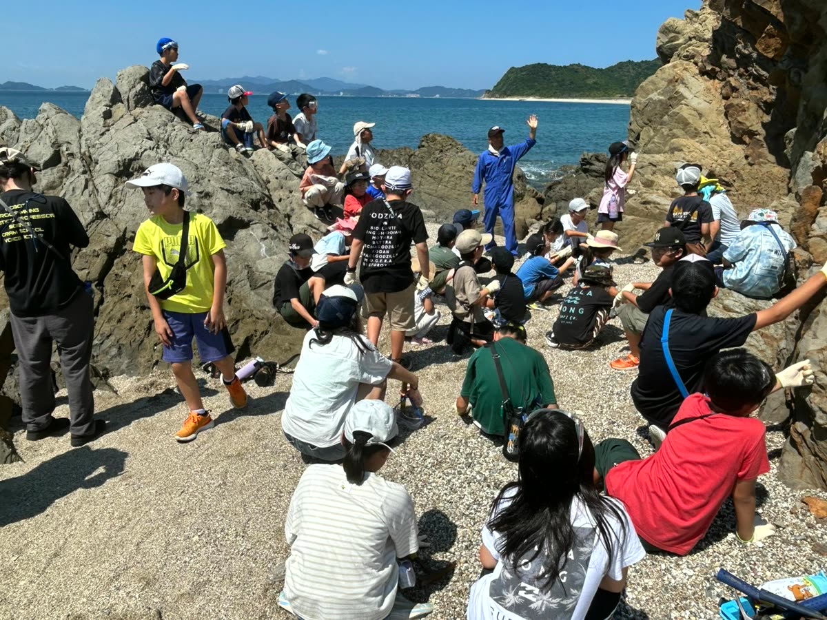 磯に集まってサマーキャンプの観察をする子どもたち
