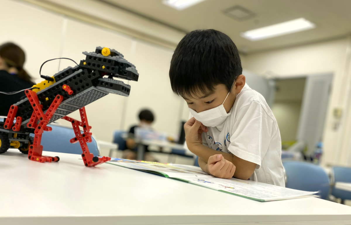 恐竜型ロボットとテキストを見比べる生徒