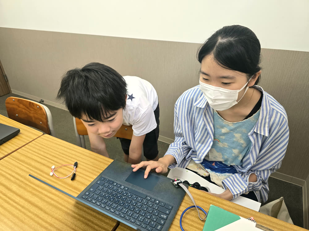講師と一緒にパソコンで動きを設定する生徒